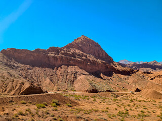Highway in a desert region with mountains of stratified sedimentary rocks