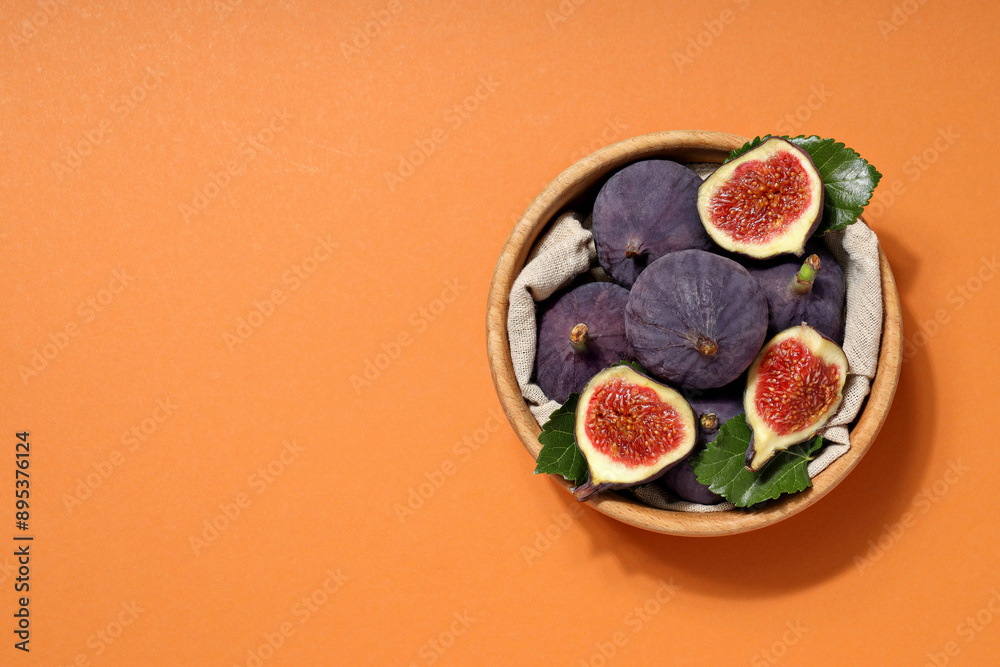 Poster Fresh ripe figs in a wooden bowl on an orange background