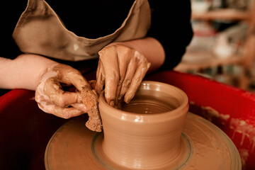Hands, clay and pottery wheel with skills for craft, tools or sustainable production at small business. Person, artist and entrepreneur for eco friendly material, sculpture or manufacturing in studio