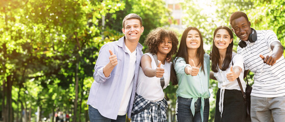 Portrait Of Happy International Friends Posing Together In Park Outdoors And Showing Thumb Up Gesture, Having Fun Outside