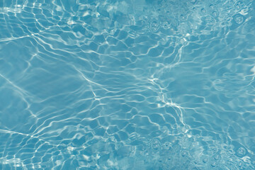 Blue water with ripples on the surface. Defocus blurred transparent blue colored clear calm water surface texture with splashes and bubbles. Water waves with shining pattern texture background.