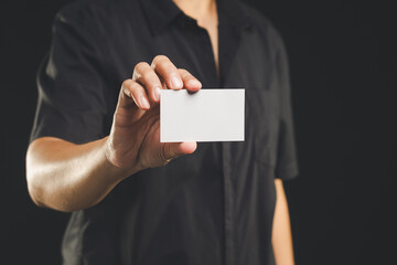 Person is holding a blank white name card mockup while standing on a black background.