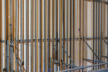 Theater stage rigging with theatrical equipment, lighting, supports, and chains. Photo taken from an elevated position looking across the rigging.	