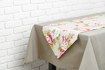 Floral Table Runner on a Beige Tablecloth Against a White Brick Wall