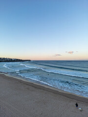 Aerial drone view sun setting over the beach with silhouettes of people and surfers 