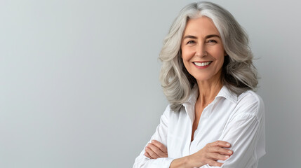 Handsome woman 50s mid age beautiful physically fit well groomed senior model grey hair stylish smiling Healthy face skin care skincare hair care fitness dental off center copy space gray background