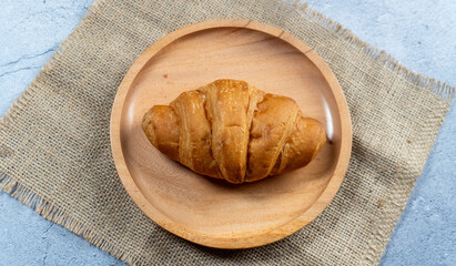 Naklejka premium top view of a croissant in wooden plate on top gunny sack