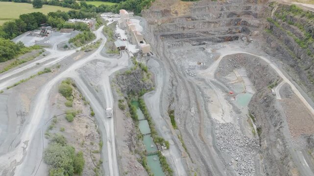 Aerial view of truck carrying freshly mined aggregate from quarry base, showcasing the industrial landscape and mining operations