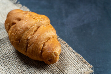 close shot a croissant on top gunny sack on dark table