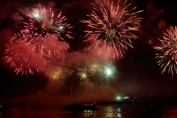 Holiday fireworks above water with reflection on the black sky background