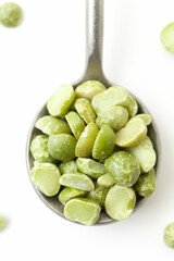 Dry, green peas in iron spoon on white background. Close-up