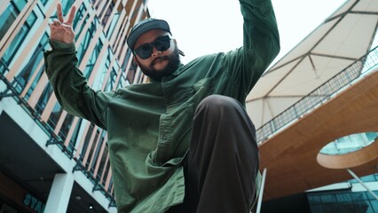 Low angle view of hipster pose in hip hop style surrounded by mall view. Portrait of sporty asian...