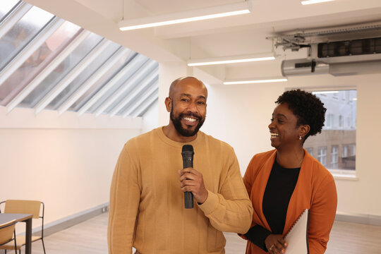 Smiling multiethnic creative team members with microphone during presentation in modern studio