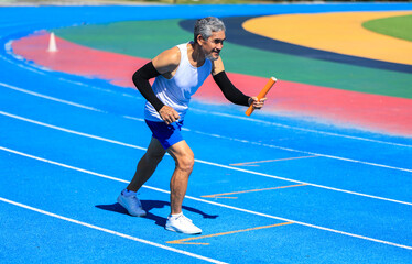 Fototapeta premium Senior Asian athlete is practicing running in the professional blue track for professional exercise, sport training workout and healthy for longevity concept