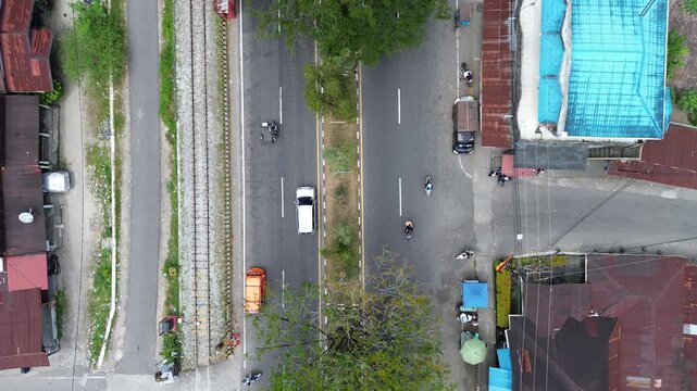 Aerial view of normal traffic at a T-junction with railway tracks beside the road