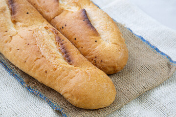 French baguette bread sliced ​​on a wooden cutting board against a white background. Preparing the iftar table.