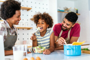 Happy african american family preparing healthy food in kitchen, having fun together on weekend