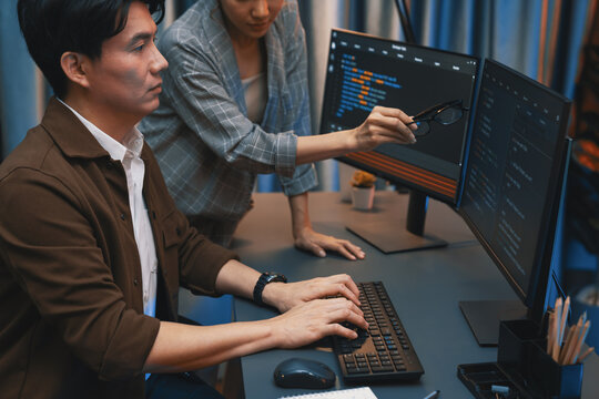 IT developers discussing with point to intelligent website development coder system running data online two screens information technology at neon light room at modern office. Infobahn.