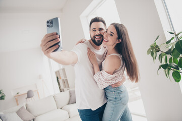 Photo of two idyllic partners hug make selfie modern bright interior weekend flat indoors