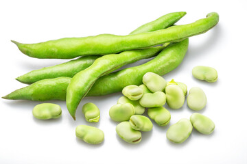 Green broad bean pod and several broad beans isolated on white background.