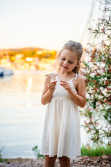 Portrait of little girl in white dress happy smiling on blooming park background in Croatia