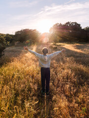 Boy with Outstretched Arms in Sunset Meadow