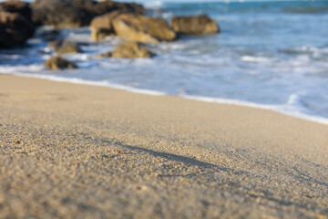 photo of the beach, with a splendid provocative white sand, the sea with a beautiful light blue and in the background a formation of rocks that give the beach a touch