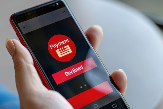 Person is holding a smartphone with a notification on the screen indicating that a payment has been declined