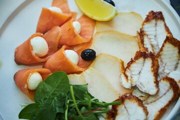 A plate of food with a variety of fish and vegetables. The plate is white and the food is arranged...