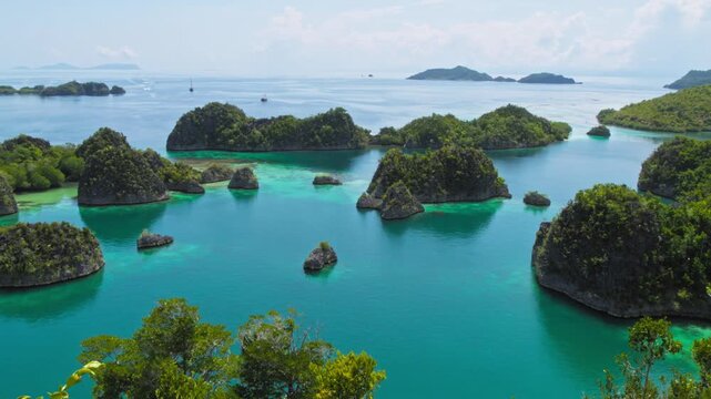 Breathtaking panorama of Pianemo archipelago in Raja Ampat, Indonesia, with the camera panning left. The shot captures green foliage, turquoise waters, and scattered limestone islands across the ocean