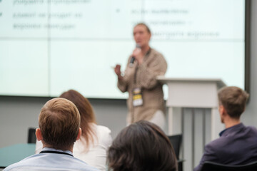 Speaker on stage giving presentation at business conference with attentive audience listening