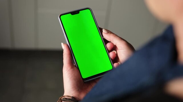 Girl Holding And Looking At A Greenscreen Chromakey Smartphone In Her Hands