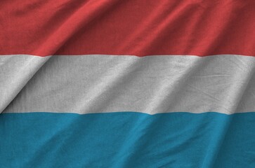 Luxembourg flag depicted on folded wavy fabric of old cloth close up