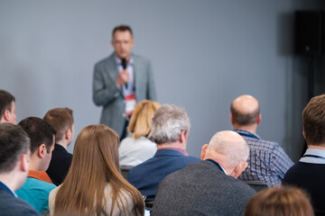 Fototapeta premium Business professionals attentively listening to a speaker at a conference. Audience members focused on presentation, learning and networking.