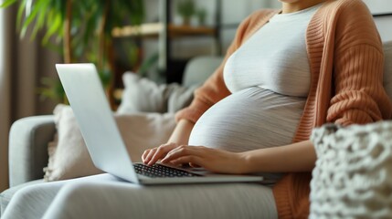 Naklejka premium Pregnant woman with laptop at home