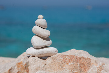A stone stack on the beach with a blue ocean backdrop radiates calmness, perfect for meditation