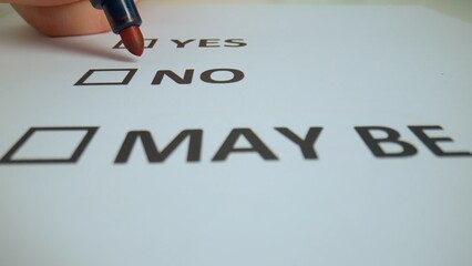 Close up shot of woman hand working with document, red marker in female hand writing check mark in text box with word no in document.