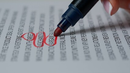 Close up shot of woman hand working with document, red marker in female hand circled highlighted...