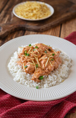 Brazilian style Chicken strogonoff with rice and potato straw on wooden table.