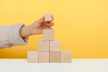 Wooden Stacked Blocks Against Simple Yellow Background