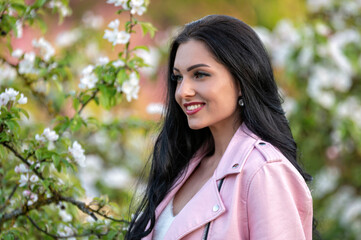 Woman in pink jacket near blooming tree. Background with selective focus and copy space