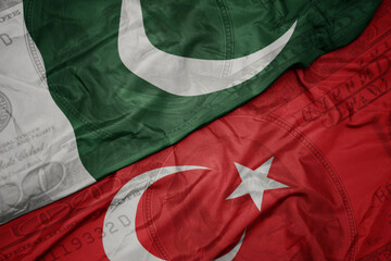 waving colorful flag of pakistan and national flag of turkey on the dollar money background....