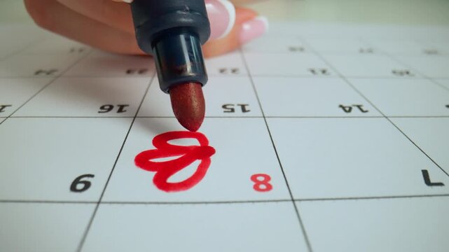 Red marker highlighting with flower calendar 8th day of the month on the paper page. International women's day date chosen in calendar.