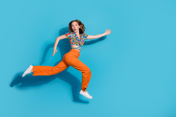 Full size photo of nice young girl run jump empty space wear top isolated on blue color background