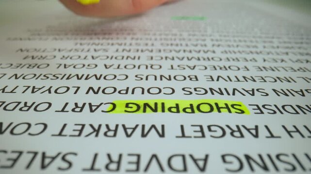 Close up shot of woman hand working with document, yellow marker in female hand marked highlighted a word shopping in text.