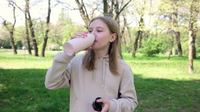 Adorable Small Schoolgirl Sipping Water From A Bottle In The Park