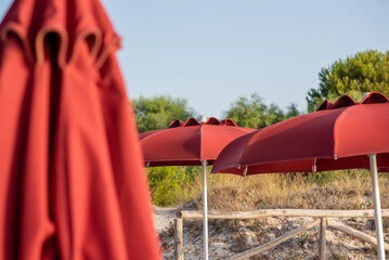 A picturesque beach scene with red umbrellas and trees