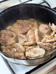 Homemade traditional family meal of pork chops cooking on a stovetop in a skillet