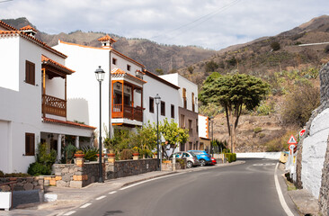 street in Tejeda little village on scenic Gran Canaria, Canary Islands, Spain with white houses, red brown roofs, road way and view on mountains 