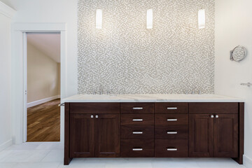 Interior view of bathroom with wooden vanity unit with stainless steel taps and mosaic tiles.